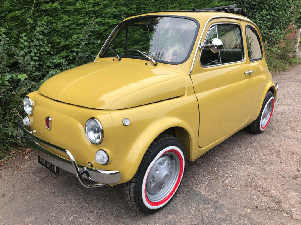 Vintage Yellow Fiat 500 Wallpaper: Nostalgic Rustic Adventure Background