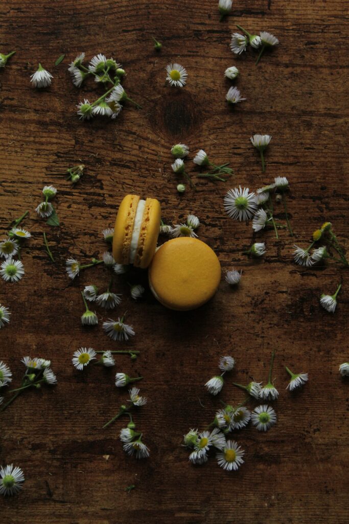 Charming Yellow Macarons on Rustic Wood with Chamomile Flowers Wallpaper
