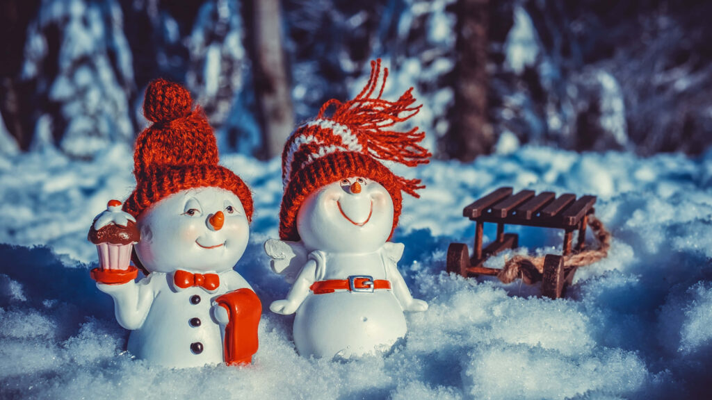 Charming Winter Wallpaper: Cheerful Snowmen & Festive Sled Scene