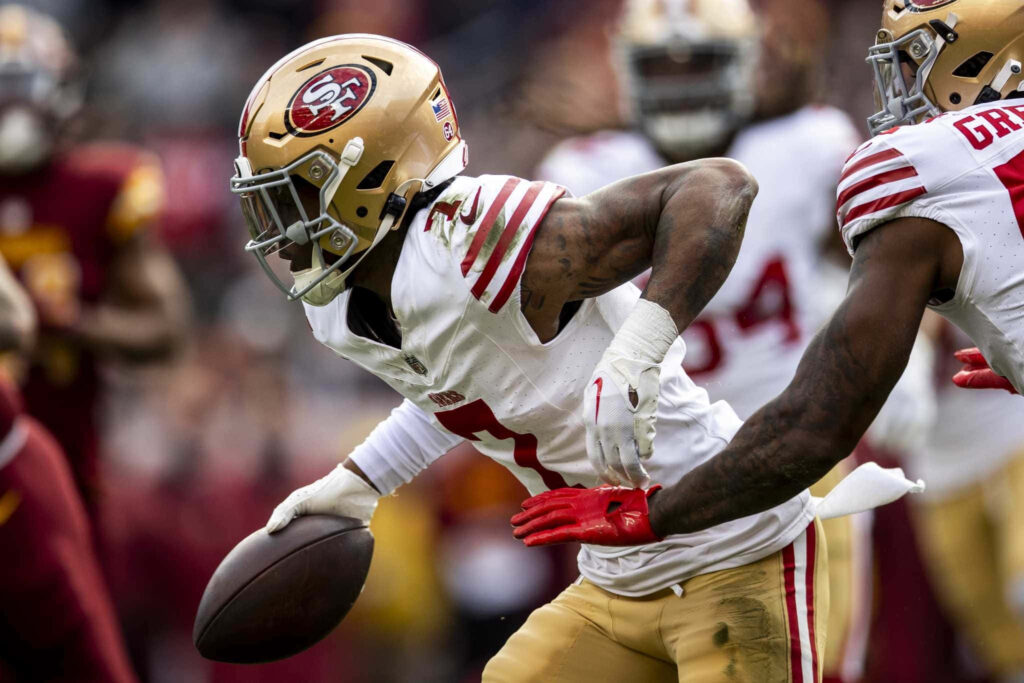 Charvarius Ward San Francisco 49ers cornerback mid-play in red gold uniform on football field Wallpaper