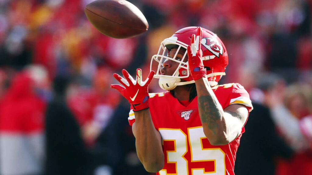 Charvarius Ward in Kansas City Chiefs uniform catching football with intense focus in NFL game Wallpaper
