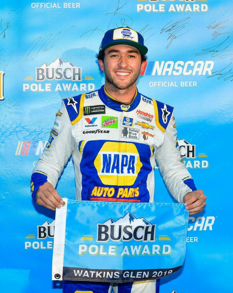 Chase Elliott in racing suit holding Busch Pole Award flag with NASCAR logos on vibrant blue background Wallpaper