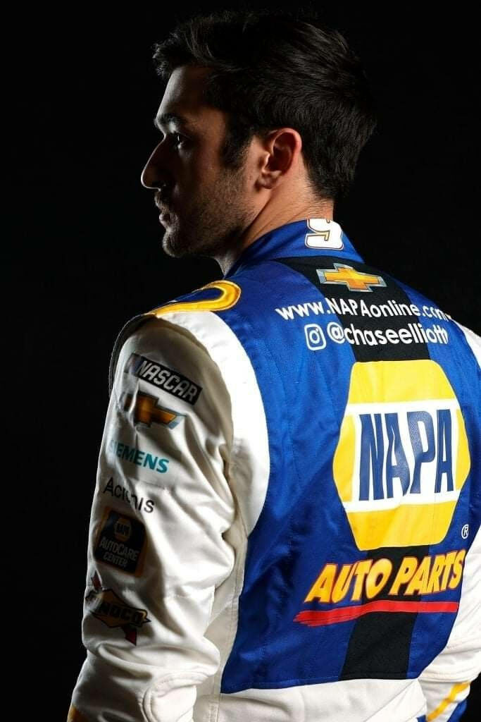 Chase Elliott NASCAR driver in blue NAPA racing suit with dramatic lighting and dark background Wallpaper
