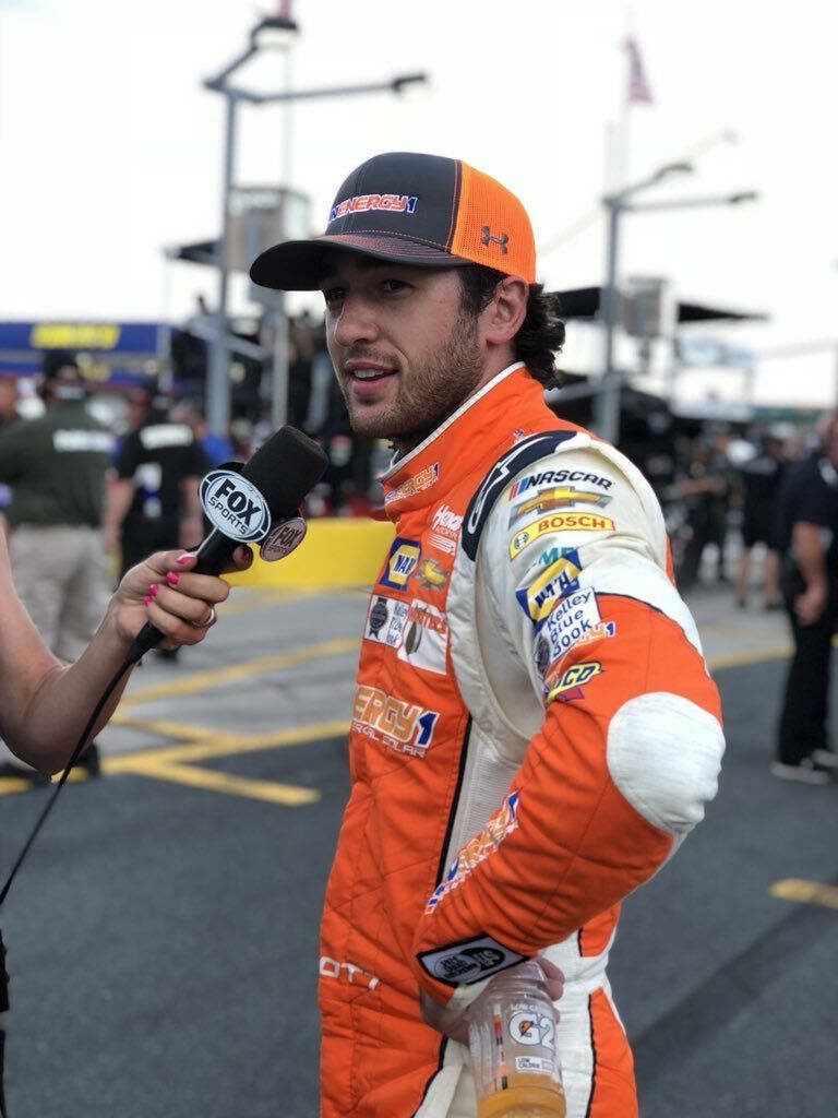 Chase Elliott in orange white racing suit during lively NASCAR pit lane interview wallpaper background