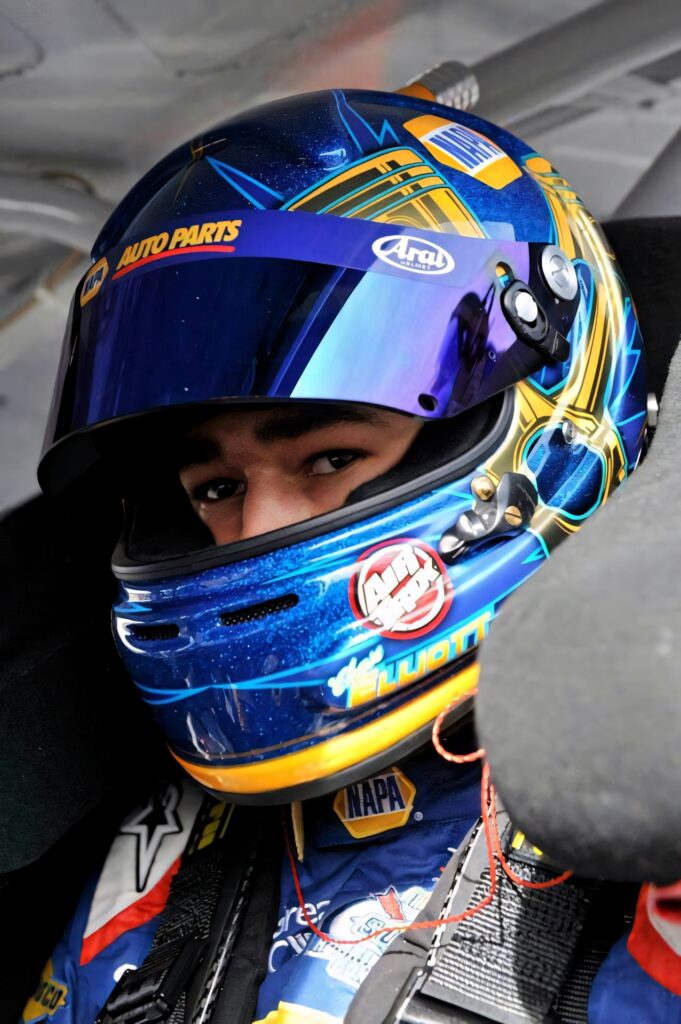 Chase Elliott NASCAR driver in blue gold racing helmet inside detailed race car interior wallpaper