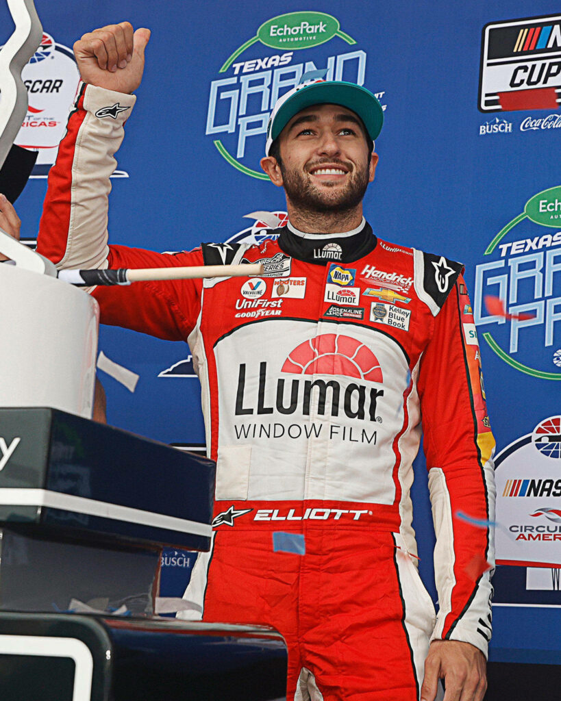 Chase Elliott in red white racing suit with Llumar Window Film celebrates NASCAR win with fist raised Wallpaper