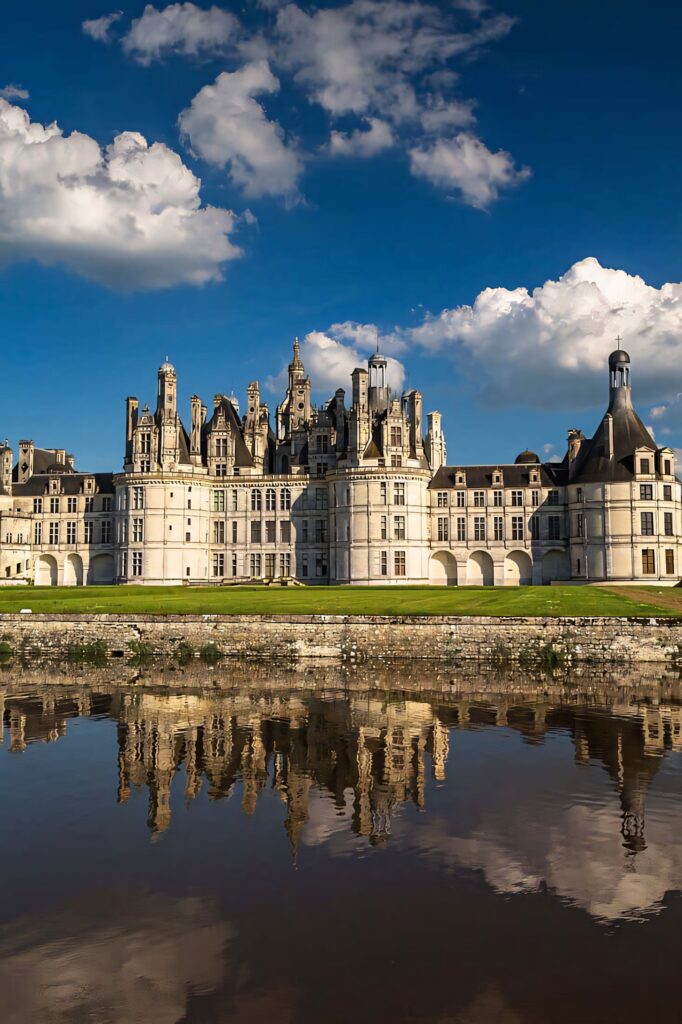 Château de Chambord French Renaissance castle with ornate towers reflected in calm water under blue sky Wallpaper