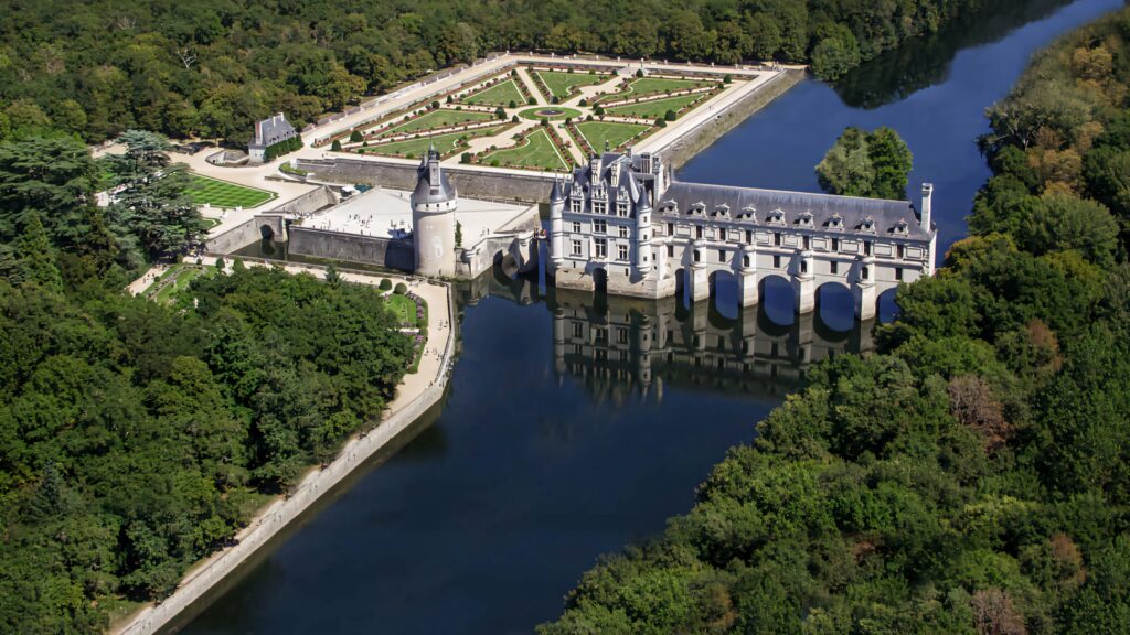 Aerial view of Château de Chenonceau over river surrounded by lush gardens and greenery wallpaper