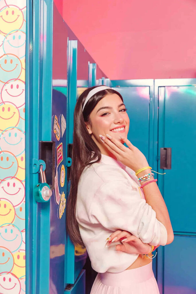 Charli D'Amelio Cheerful Wallpaper: Stylish Pose by Colorful Lockers