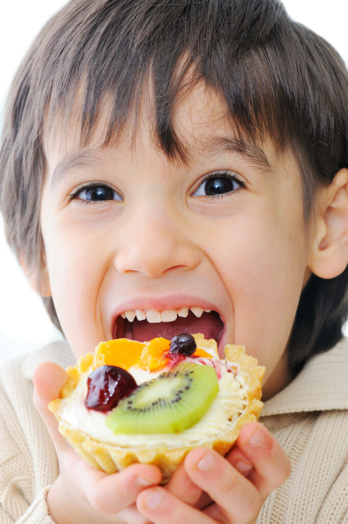 Cheerful Child Enjoying Colorful Fruit Tart - Wallpaper Background