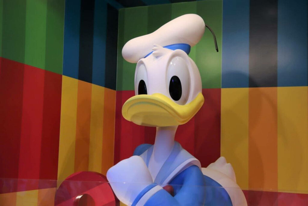 Cheerful Donald Duck in classic sailor outfit on vibrant colorful striped wallpaper background