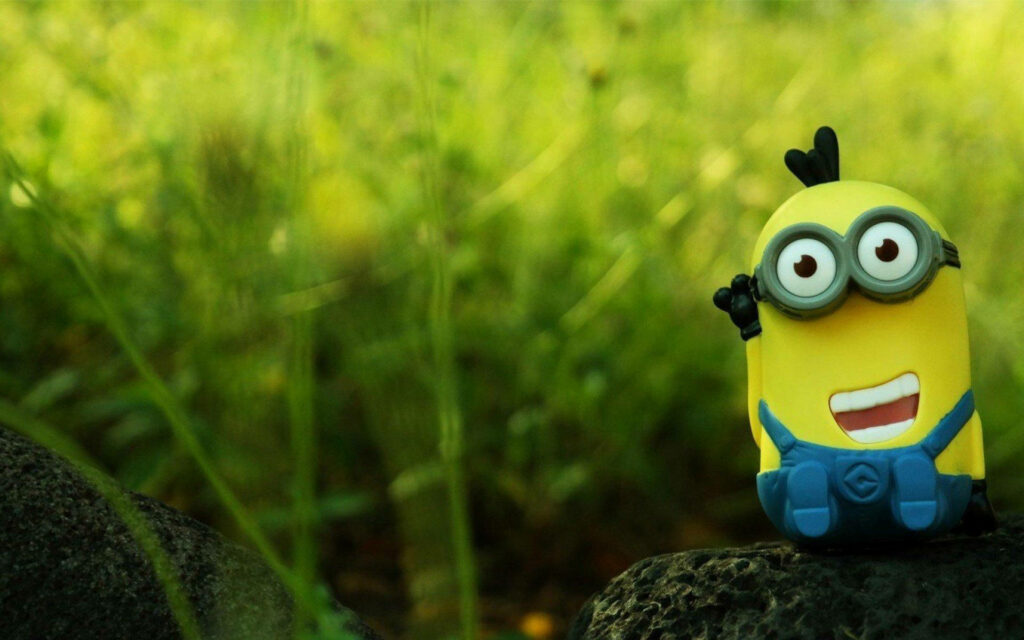 Cheerful Kevin Minion Toy Wallpaper Against Lush Green Background