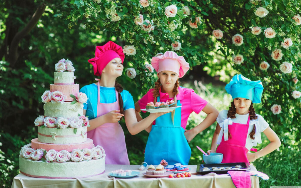 Cheerful Young Pastry Chefs with Colorful Cake in Lush Garden Wallpaper