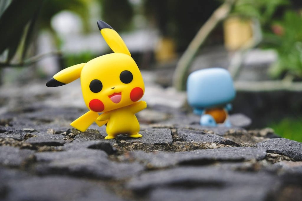 Pikachu Funko Pop figure vibrant yellow on stone path with blurred Squirtle background wallpaper