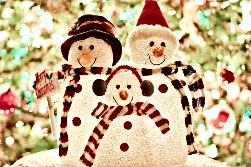 Cheerful Snowman Family Wallpaper with Holiday Lights Background