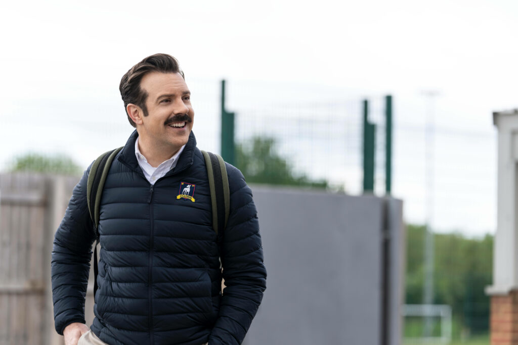 Cheerful Ted Lasso in Jacket | Vibrant Wallpaper Background