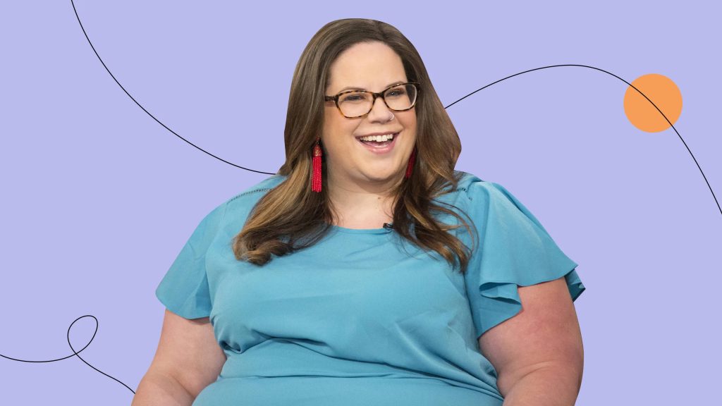 Whitney Way Thore smiling in blue top red earrings with lavender background and orange circle Wallpaper