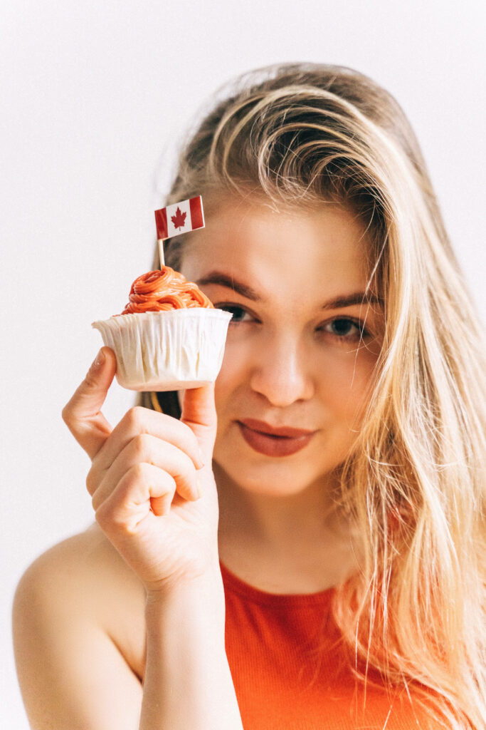 Cheerful Young Woman with Cupcake and Canadian Flag Wallpaper