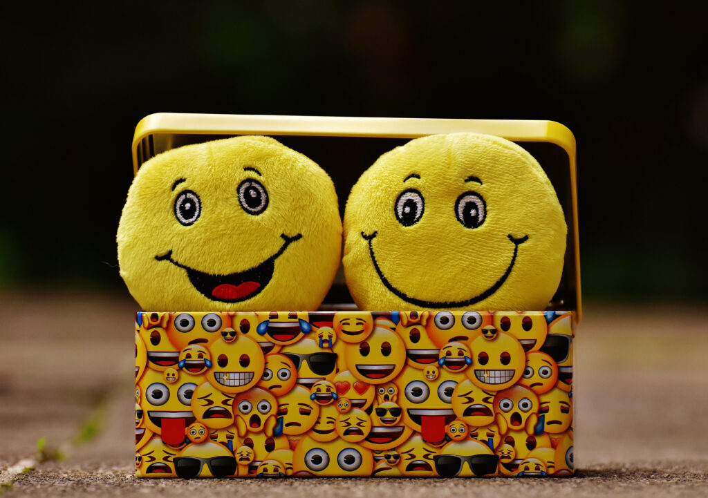 Cheerful Yellow Emoji Wallpaper with Playful Patterned Box Background