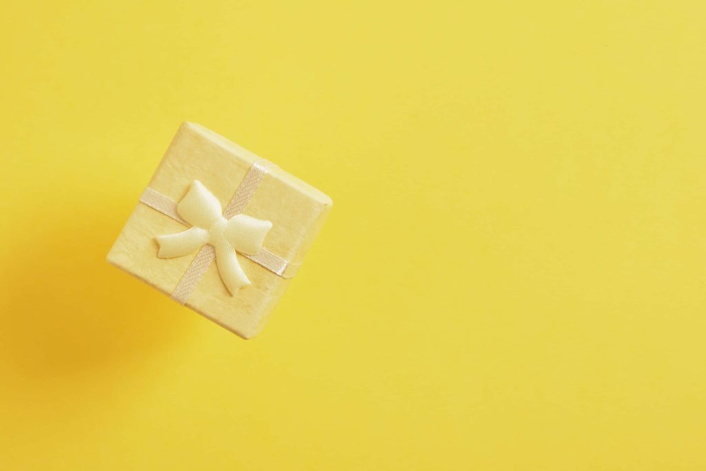 Minimalist square yellow gift box with bow on vibrant yellow background for festive wallpaper