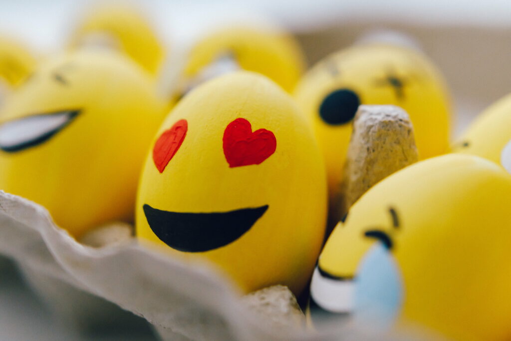 Colorful macro photo of emoji painted eggs in carton heart eyes laughing fun wallpaper background