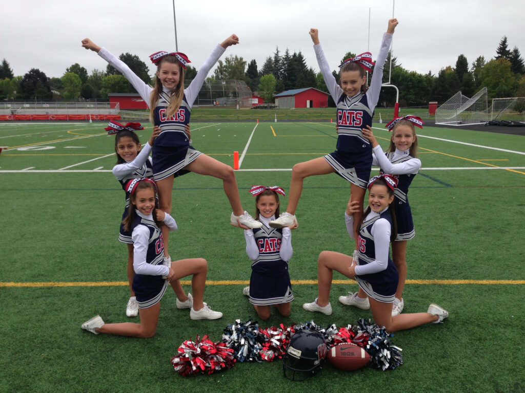 Dynamic Cheerleaders Showcase Teamwork on Football Field Wallpaper