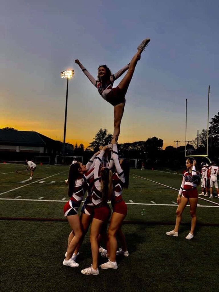 Cheerleaders Stunt at Sunset: Athleticism & Teamwork Wallpaper