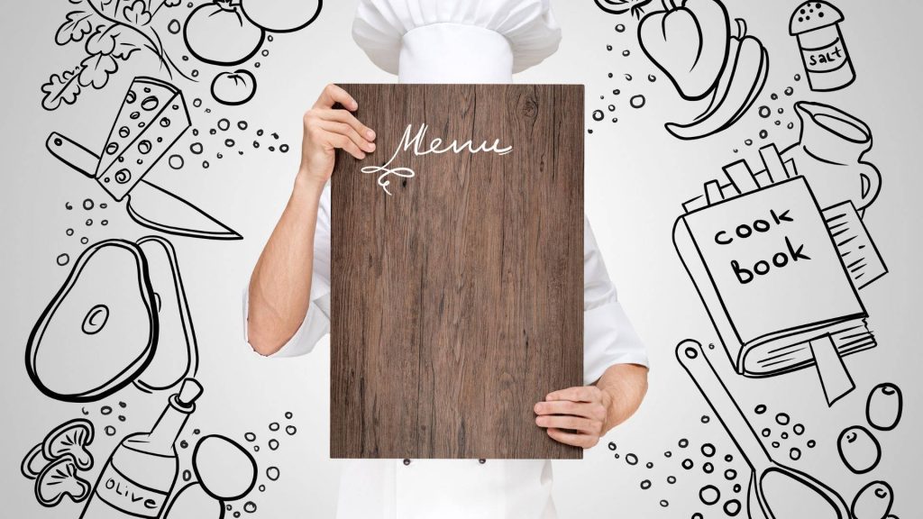 Chef in white uniform holding blank wood menu board with black food sketches background wallpaper
