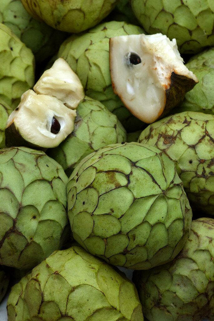 Close-up of cherimoya custard apples showing green scaly skin white creamy interior and black seeds Wallpaper