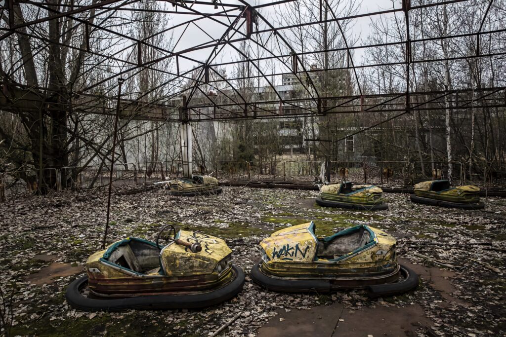 Abandoned Chernobyl bumper cars overgrown with leaves rusted metal post-apocalyptic decay wallpaper