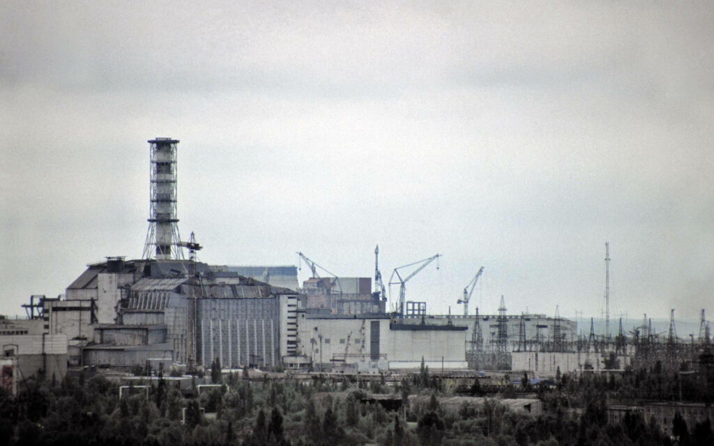 Chernobyl disaster reactor ruins with cranes under gray skies haunting post-apocalyptic wallpaper