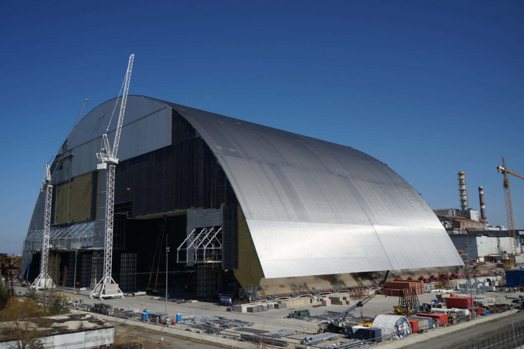 Chernobyl New Safe Confinement steel arch with cranes and scaffolding under clear blue sky Wallpaper