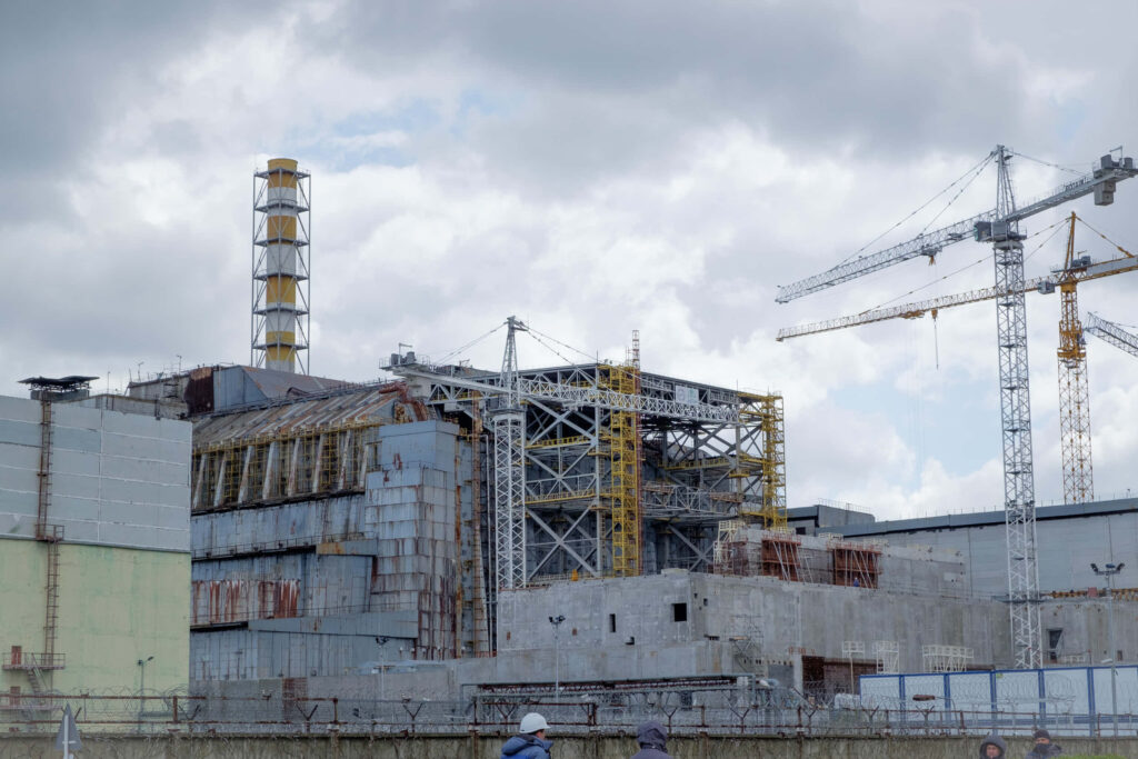 Chernobyl nuclear power plant with damaged reactor cranes workers industrial site wallpaper background