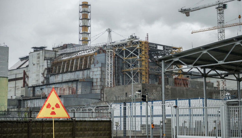Chernobyl nuclear power plant with decayed structures and radiation warning under cloudy sky wallpaper