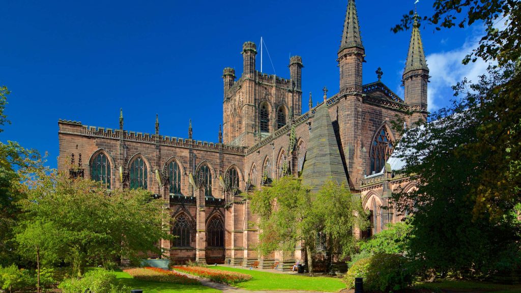 Chester Cathedral Gothic architecture red sandstone vibrant blue sky lush garden flowers Wallpaper
