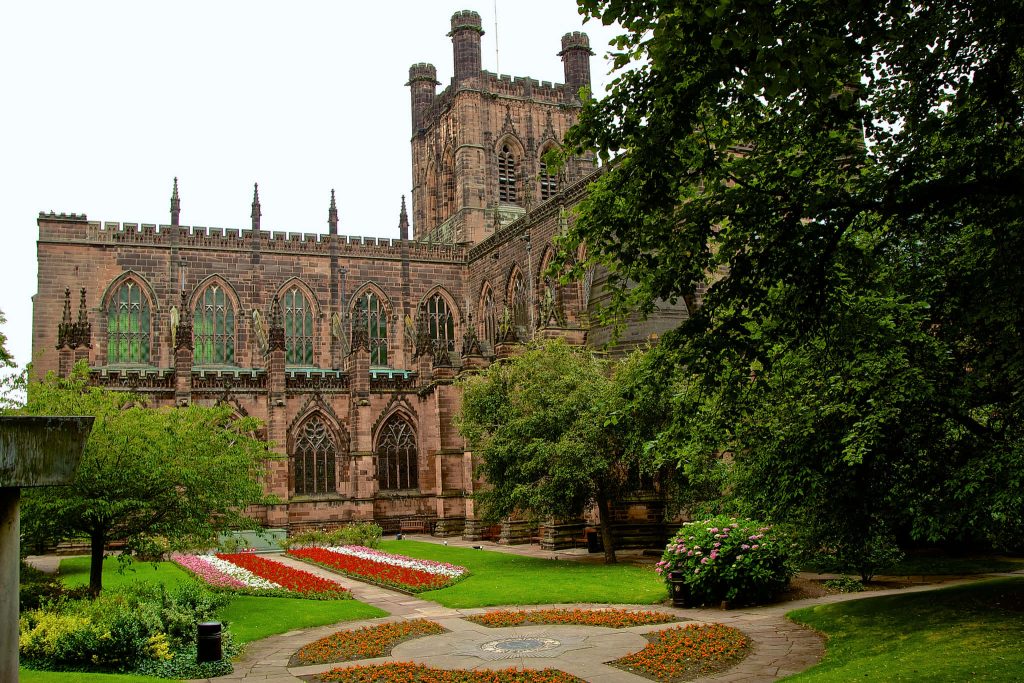 Chester Cathedral red sandstone Gothic architecture with vibrant gardens and stone pathways Wallpaper
