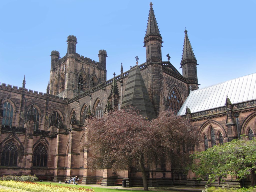 Chester Cathedral sandstone facade bright daylight vibrant greenery clear blue sky peaceful scene Wallpaper