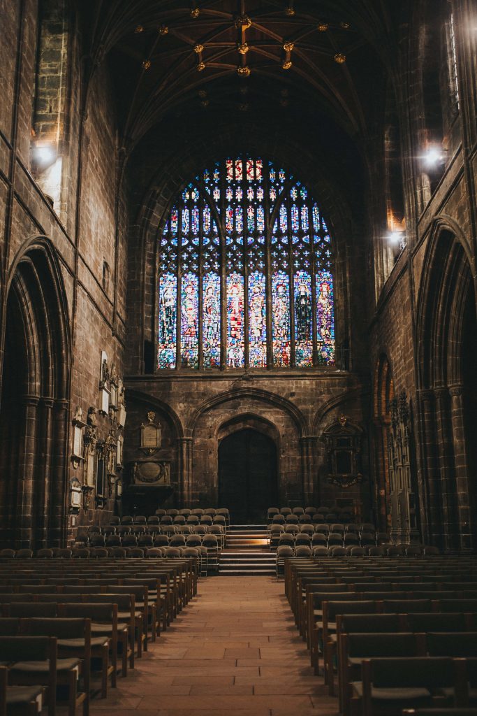 Chester Cathedral stained glass window lighting historic stone interior with empty pews wallpaper