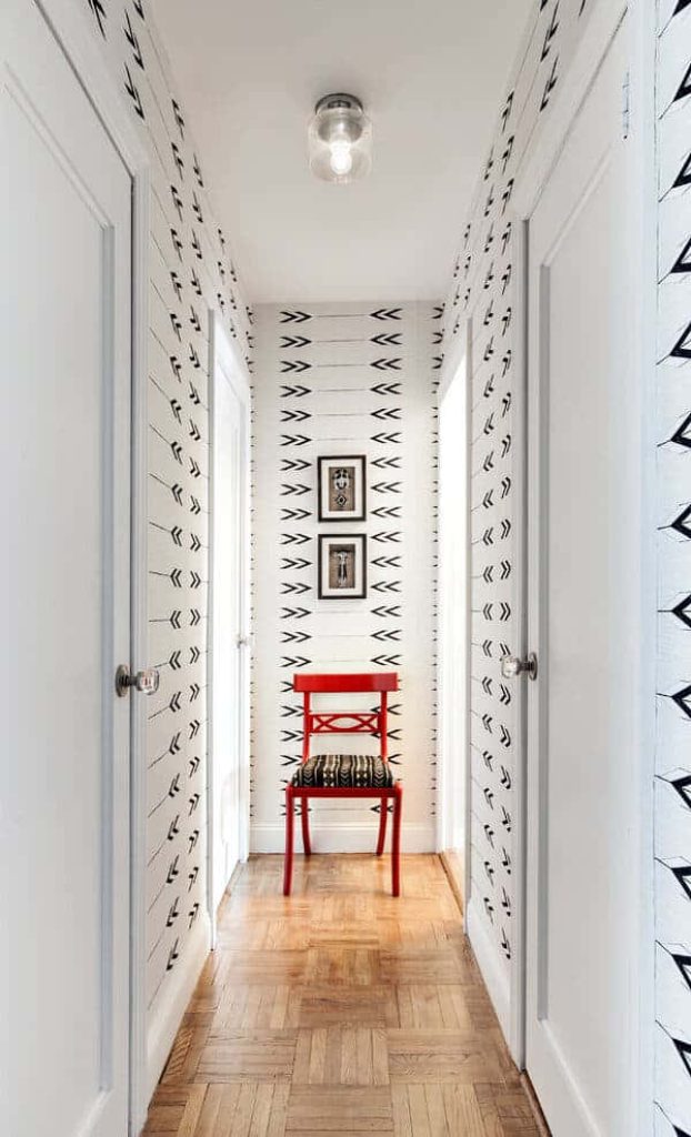 Vibrant red wooden chair against black and white chevron wallpaper in stylish modern hallway
