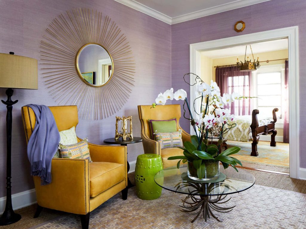 Chic interior with yellow armchairs lavender wallpaper gold sunburst mirror glass table orchids
