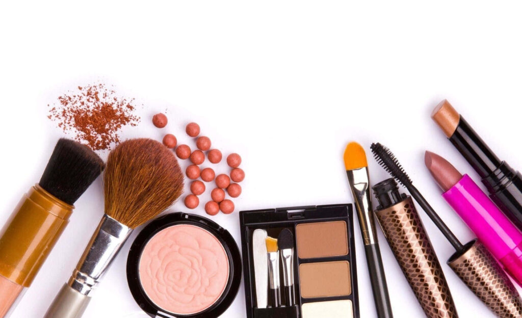 Flat lay of makeup essentials with brushes blush eyeshadow lipsticks mascara on white background Wallpaper