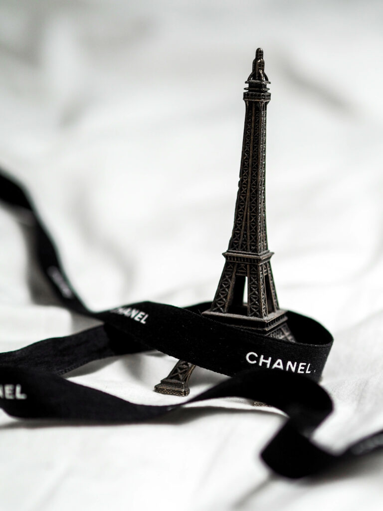 Black Chanel ribbon wrapped around mini Eiffel Tower Parisian chic wallpaper background