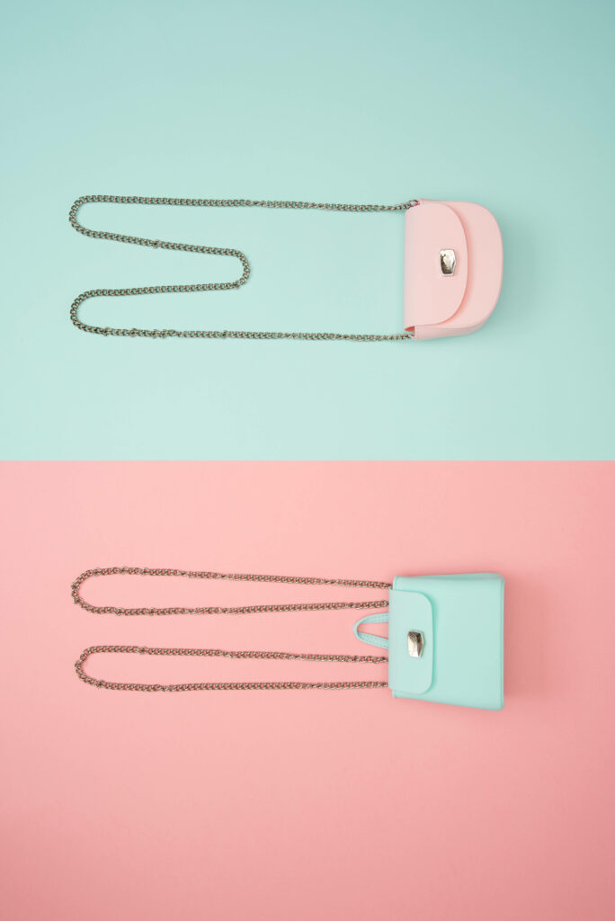 Stylish pastel pink and blue handbags with chain straps on contrasting color backgrounds wallpaper