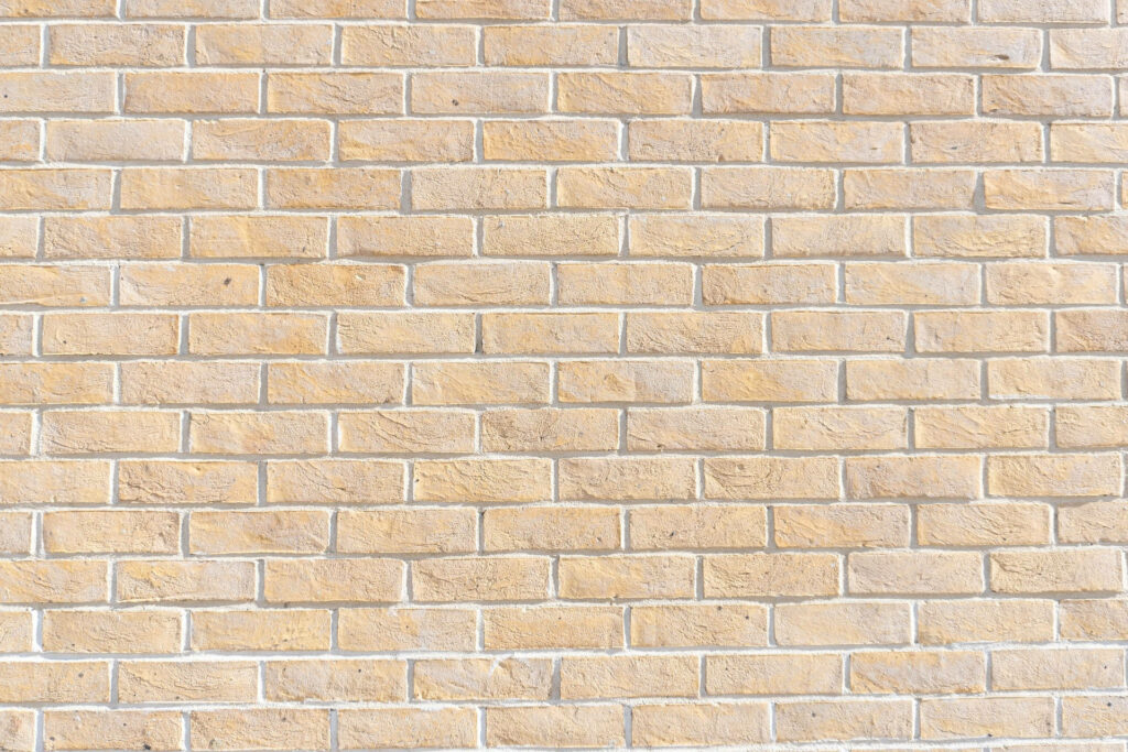 Charming Yellow Brick Wall with Chic White Borders: A Wallpaper Must-Have