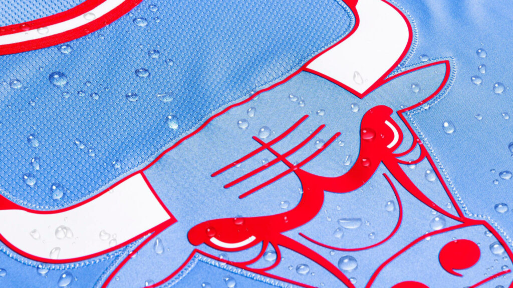 Close-up of Chicago Bulls logo on textured blue red jersey with water droplets wallpaper background