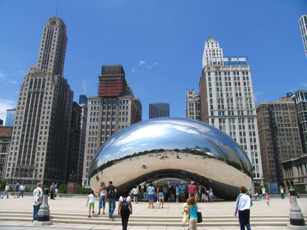 Chicago cityscape featuring Cloud Gate The Bean sculpture and tourists under blue sky Wallpaper