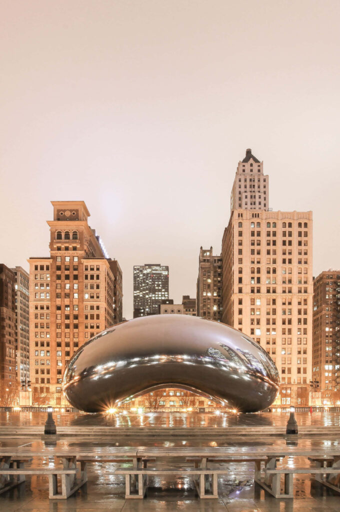 Cloud Gate in Chicago at night glowing with city lights and historic buildings in background wallpaper