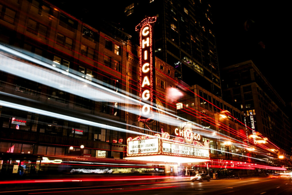 Chicago Theatre illuminated at night with vibrant city lights and dynamic car light trails Wallpaper