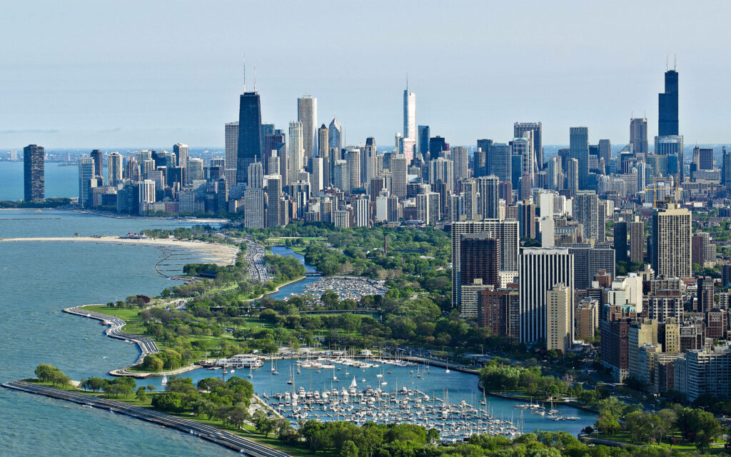 Aerial view of Chicago skyline with skyscrapers green parks and Lake Michigan shoreline wallpaper