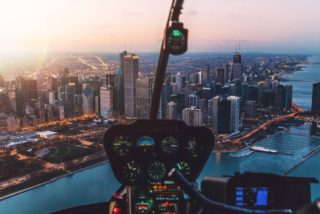 Helicopter cockpit view of Chicago skyline at dusk with glowing instruments and Lake Michigan Wallpaper